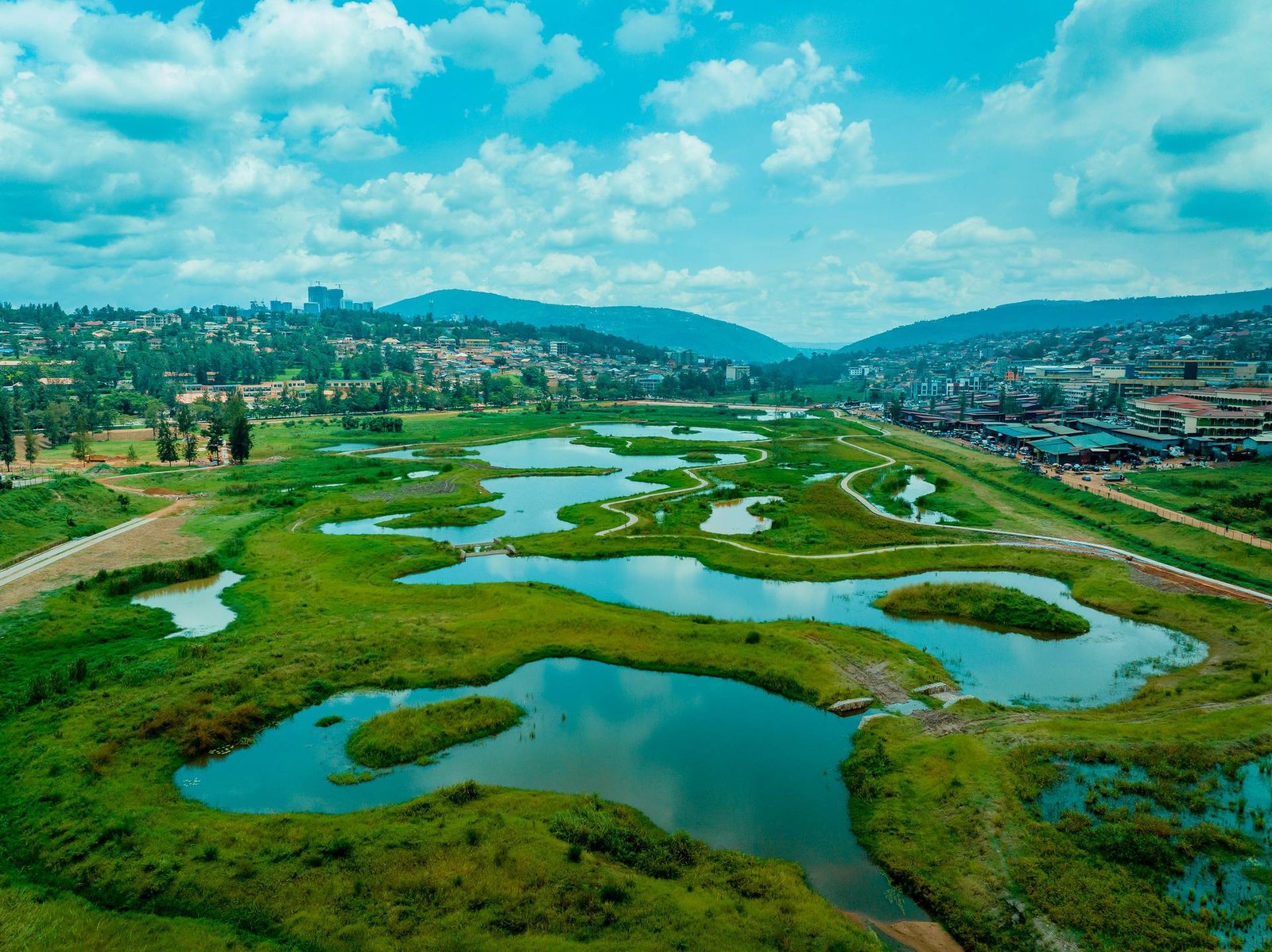 Wetlands and green hills on the edge of Kigali under a bright sky